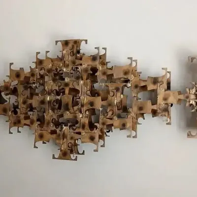 Mid-century modern brutalist welded brass wall sculpture, featuring layered geometric shapes with torch-cut finishes, in the style of...