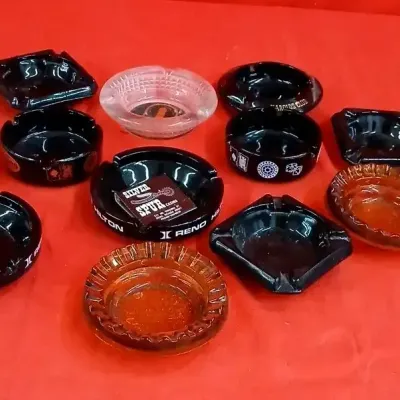 Collection of vintage glass casino and hotel ashtrays, including black milk glass and amber pieces featuring branding from Reno Hilton...