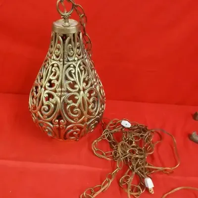 Vintage Hollywood Regency style swag pendant lamp with ornate filigree metal shade and long hanging chain.