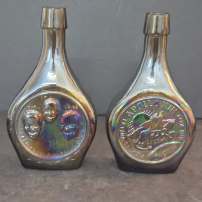 Sale Photo Thumbnail #17: Pair of iridescent Wheaton carnival glass commemorative bottles featuring the 1970 Apollo 13 mission, showing the front and back designs.