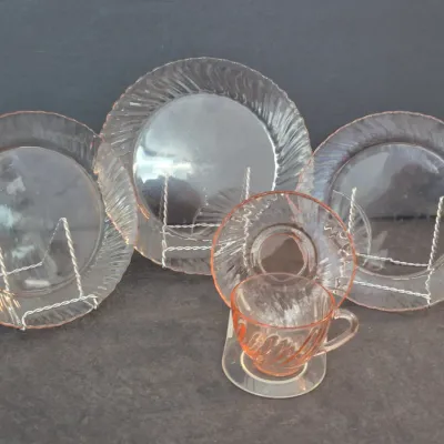 Sale Photo Thumbnail #8: Five-piece vintage pink Depression glass set featuring three plates, a saucer, and a matching teacup with swirled rim details.