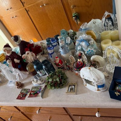Sale Photo Thumbnail #101: An assortment of Christmas decorations and winter tabletop decor displayed on a vanity counter, including Santa figurines, snowmen, glass ornaments, candles, and nativity items.