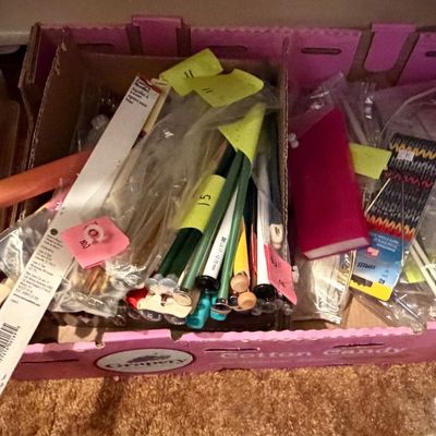 Large assortment of knitting needles, crochet hooks, and crafting supplies organized in cardboard trays.
