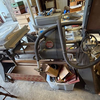 Vintage Shopsmith multi-purpose woodworking machine with attached dust collection hoses and various accessories.