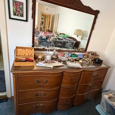 Vintage French Provincial style wooden triple dresser with attached carved mirror frame, featuring serpentine drawer fronts and brass...