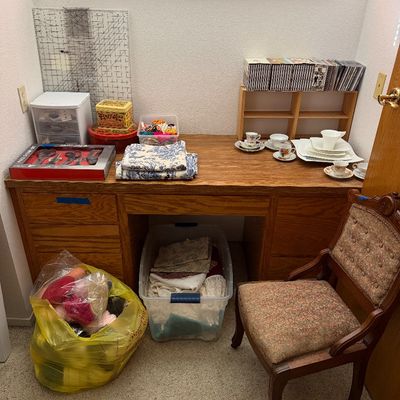 Sale Photo Thumbnail #111: Large wooden office desk paired with a vintage upholstered side chair, alongside crafting supplies, organized fabric, and assorted teacups.