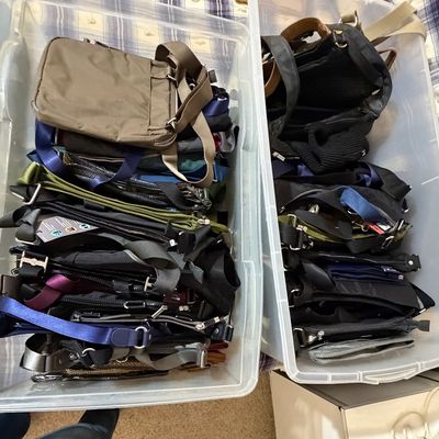 Two clear plastic storage bins filled with an assortment of modern crossbody bags and purses. Bagalini and Sak