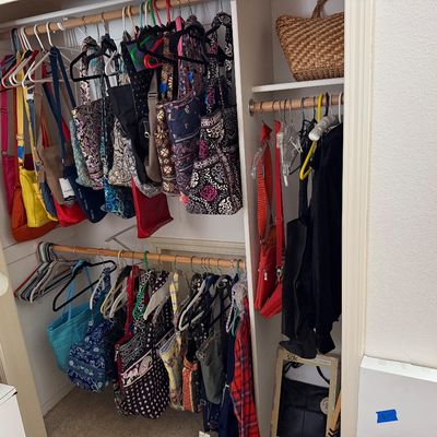 Closet full of organized handbags, totes, and purses, including several quilted Vera Bradley styles, leather bags, and a woven basket on...