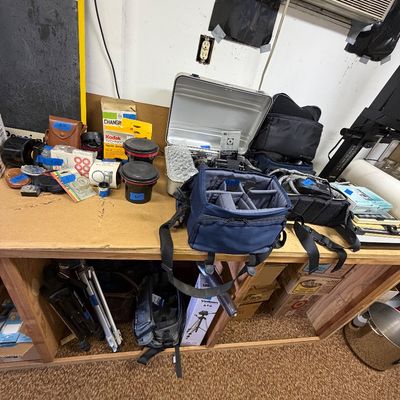 Collection of vintage camera equipment and photography accessories, including camera bags, film processing supplies, an aluminum hard...