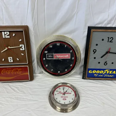Collection of vintage advertising wall clocks, including Coca-Cola, Ford Motorcraft, Goodyear Tires, and Raybestos Brakes designs.