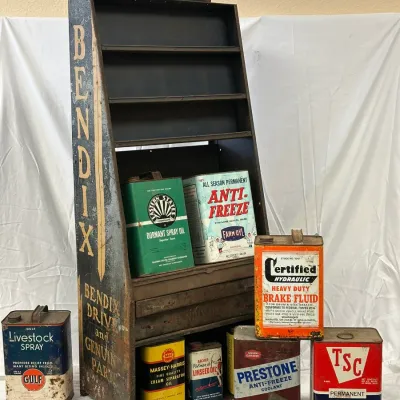 Vintage metal Bendix automotive parts display rack, filled and surrounded by various antique oil and antifreeze fluid cans.