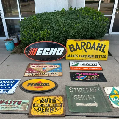 Collection of vintage advertising signs, including metal and tin automobilia, power equipment, and agricultural brands like Bardahl,...