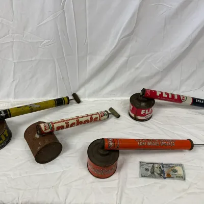Collection of four vintage hand-pump insect sprayers, including Flit, Nichols, and Spra-Well brands, showing age-appropriate wear and rust.