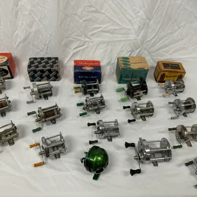 Collection of vintage fishing reels, featuring various metal baitcasting models and several original boxes from Shakespeare, Langley,...
