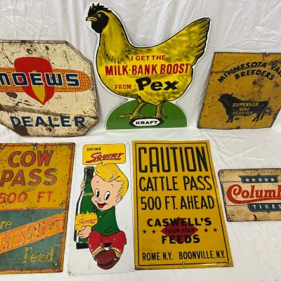 Collection of vintage metal advertising and road signs, including Moews Dealer, Kraft Pex chicken sign, Squirt soda, and farm crossing...