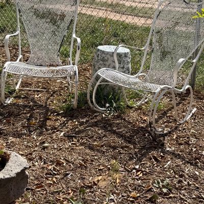 Pair of vintage white painted wrought iron outdoor patio rocking chairs featuring high mesh backs and scrolled armrests.