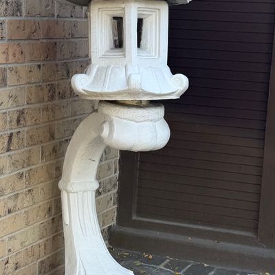 White-painted concrete pagoda-style outdoor garden lantern mounted on a curved pedestal base.