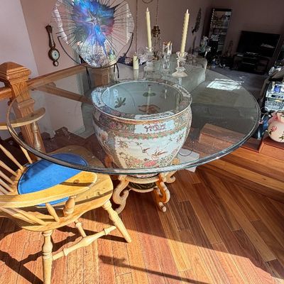 Large round glass-top dining table supported by a hand-painted Chinese porcelain fishbowl base on a carved wooden stand, paired with...
