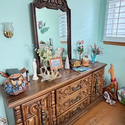 Vintage Mediterranean or Spanish Revival style dark wood dresser with intricately carved drawer fronts and matching tall ornate wall mirror.