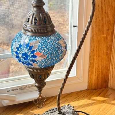 Turkish mosaic glass desk lamp featuring a blue and silver geometric shade suspended from a curved antique brass-finished stand.