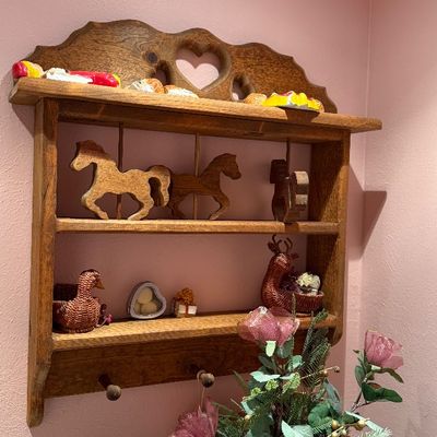 Vintage wall-hung wooden display shelf with heart cutouts, lower pegs, and various decorative figurines.
