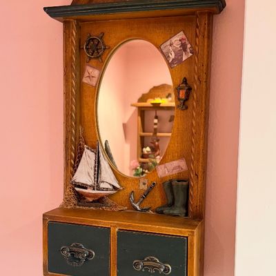 Vintage nautical-themed wooden wall vanity featuring an oval mirror, two lower drawers, and 3D embellishments including a sailboat,...