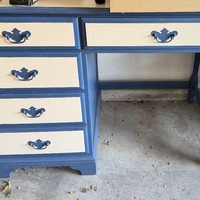 Hand-painted blue and cream writing desk featuring five drawers with blue metal bail handles and a matching bench seat visible to the right.