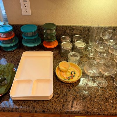 Assorted kitchenware including Pyrex glass storage containers with plastic lids, mason jars, stemware, plastic tray dividers, and a...