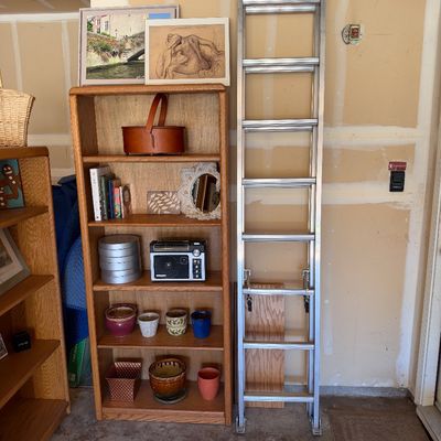 Sale Photo Thumbnail #110: Tall oak bookcase filled with various decor items and small electronics, standing beside an aluminum extension ladder.