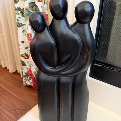 Contemporary hand-carved dark wood sculpture depicting a group of three embraced abstract figures.