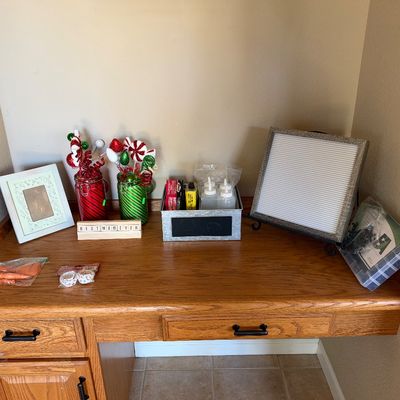 Collection of decorative items including a letter board, picture frame, festive jars with floral picks, and craft supplies sitting on a...