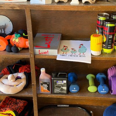 Sale Photo Thumbnail #145: Wooden shelves containing Halloween decor, tennis balls, hand weights, yoga mats, and novelty items.