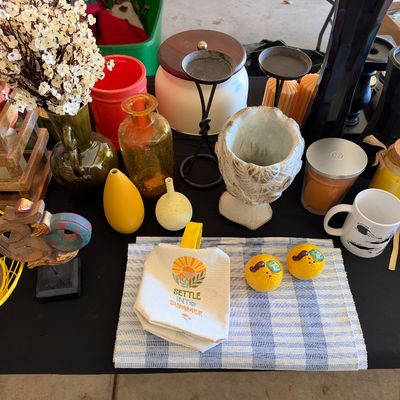 Sale Photo Thumbnail #156: Collection of home decor items including amber glass vases, candles, citrus-shaped salt and pepper shakers, a small tote bag, and a carved wooden Om symbol.