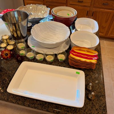 Collection of kitchenware and entertaining items including ceramic serving platters, mixing bowls, votive candle holders, and a stainless...