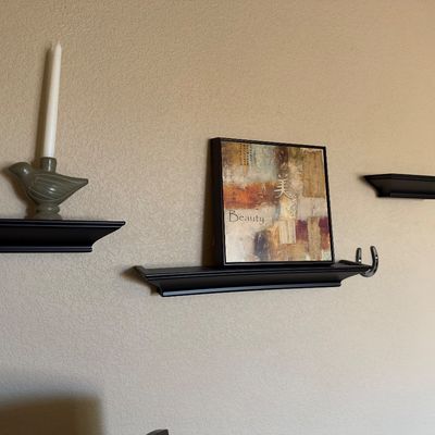 Sale Photo Thumbnail #102: Set of three wall-mounted black floating shelves featuring decorative items, including a ceramic bird candlestick holder and framed Asian-style wall art.
