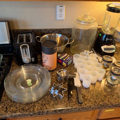 Assorted kitchenware including a Black & Decker blender and toaster, glass plates and baking dishes, stainless steel colander, small...