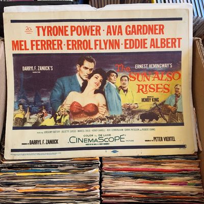 Sale Photo Thumbnail #172: Vintage 1957 original lobby card for the CinemaScope movie 'The Sun Also Rises' starring Tyrone Power and Ava Gardner, displayed in a box above vinyl records.