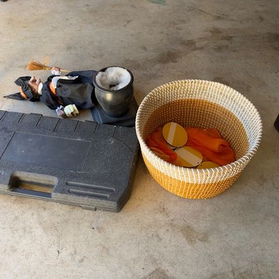 Collection of household and seasonal items including a woven storage basket filled with yellow and orange decor, a black plastic...
