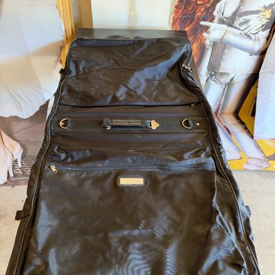 Sale Photo Thumbnail #114: Black Samsonite bi-fold garment bag with carrying handle and zippered exterior pockets.