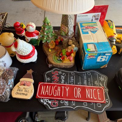 Sale Photo Thumbnail #132: Assortment of Christmas decorations and household items, including vintage Santa figurines, a festive lamp, holiday signs, and a 6 amp battery charger box.