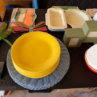 Sale Photo Thumbnail #163: Collection of household goods including bright yellow ceramic plates, a blue woven placemat, a green stepped picture frame, and decorative items.