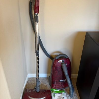 Red Kenmore Progressive canister vacuum cleaner with telescopic wand, power head attachment, and a package of replacement bags.