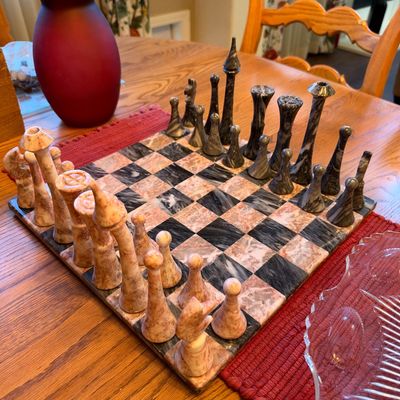 Hand-carved marble or onyx chess set with pinkish-coral and dark grey marbled playing pieces and board.