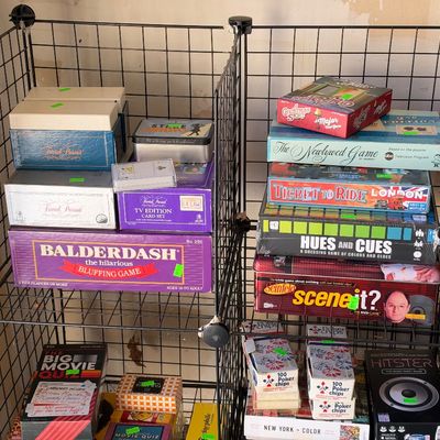 Sale Photo Thumbnail #139: Wire shelving unit filled with a assortment of vintage and modern board games, card sets, and poker accessories including Balderdash, Ticket to Ride, and Scene It.