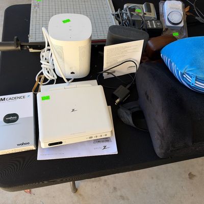 Sale Photo Thumbnail #118: Table arrangement of assorted electronics including a Sonos wireless speaker, Zenith portable DVD player, Wahoo RPM Cadence sensor in box, and Bose speaker.