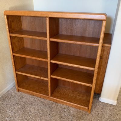 Mid-century style light oak double-width bookcase featuring eight open shelves and rounded top edges.