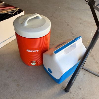 Vintage orange Gott insulated beverage dispenser jug paired with a white and blue Igloo Little Playmate Ultra personal cooler.