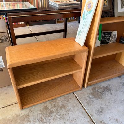 Sale Photo Thumbnail #104: Low, two-tier light oak bookcase with rounded top edges, sitting next to a taller matching bookshelf.
