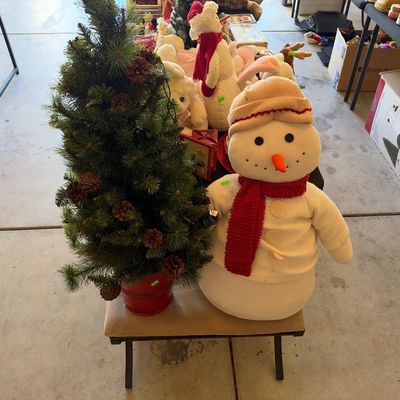Sale Photo Thumbnail #125: Small artificial Christmas tree in a red bucket next to a plush snowman figure wearing a cap and red scarf.