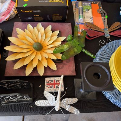 Sale Photo Thumbnail #164: Collection of home decor and household goods including a large metal flower wall sculpture, dragonfly ornaments, yellow Fiesta-style dinnerware, and a boxed Maono microphone.